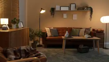 Interno di un salotto buio con lampade accese, divano e scaffale di notte